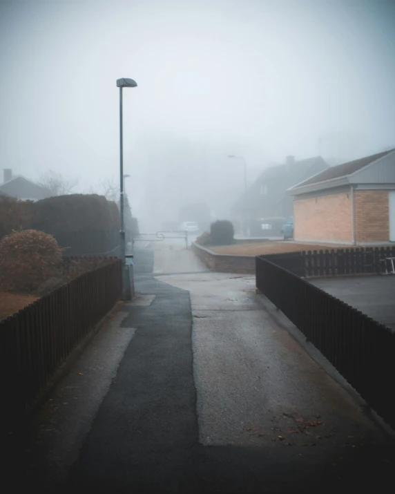 a street light sitting on the side of a road, inspired by Elsa Bleda, pexels contest winner, foggy day outside, suburbia street, white pale concrete city, standing in a township street