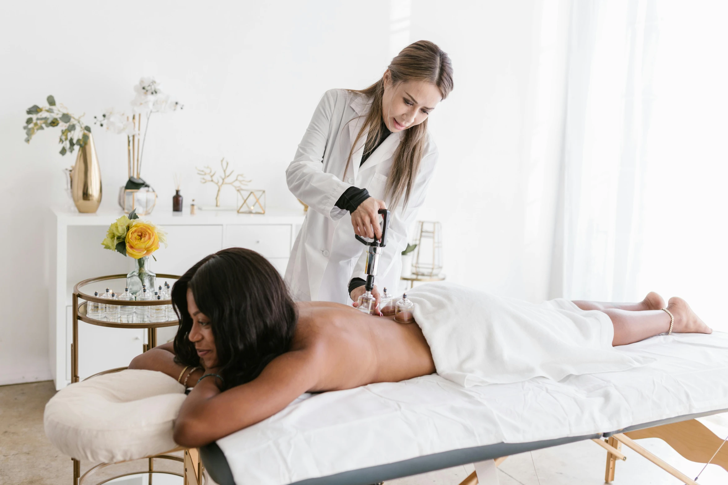 a woman getting a massage at a spa, a photo, by Emma Andijewska, pexels contest winner, with electric arc device, in white room, bare back, apothecary