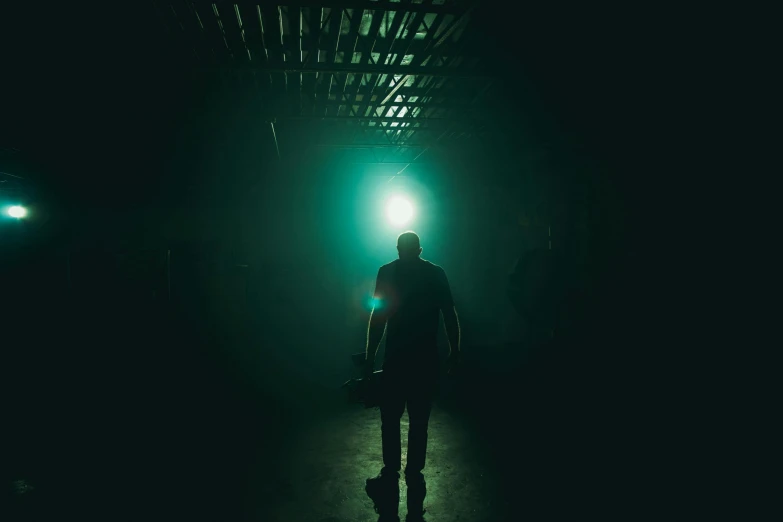 a man holding a skateboard in a dark room, inspired by Elsa Bleda, pexels contest winner, happening, green scary lights, standing in a large empty hall, green light dust, ( ( theatrical ) )