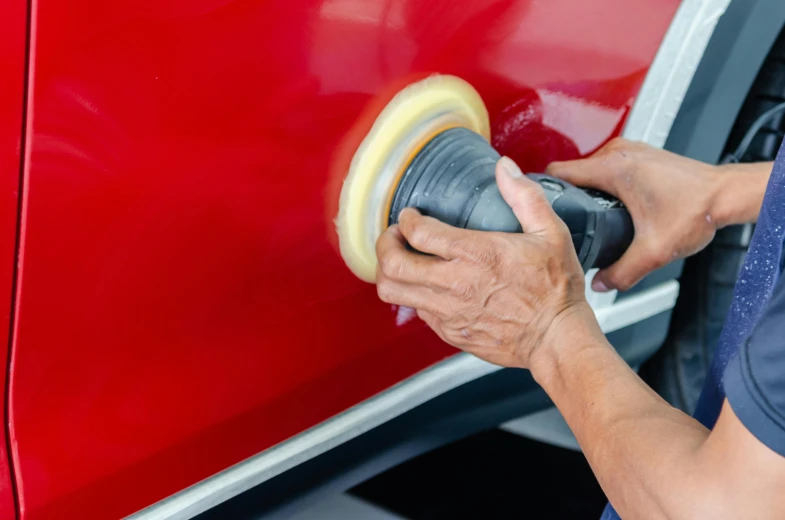 a man polishing a red car with a sander, by Julia Pishtar, pexels contest winner, fan favorite, avatar image, detail and care, smooth contours