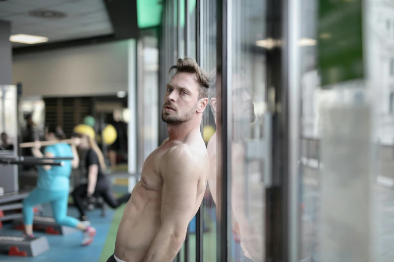 a man standing next to a window in a gym, a photo, hyperrealism, profile image, green body, manly, high quality upload