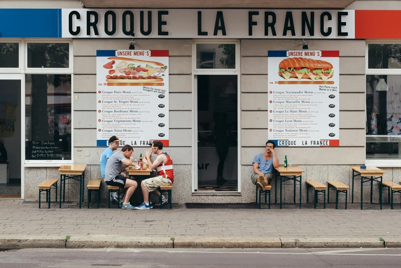 a group of people sitting at tables outside of a restaurant, a photo, by Carey Morris, pexels contest winner, art nouveau, baking french baguette, regal fast food joint, polish food, he got a big french musctache
