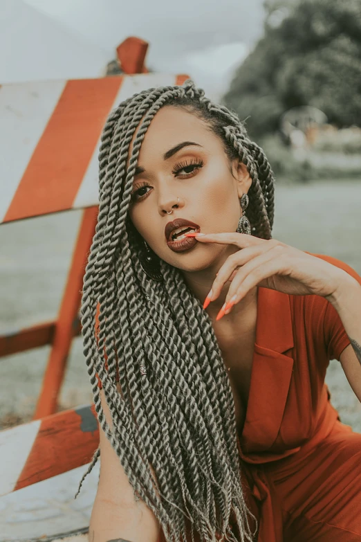 a woman in a red dress sitting on a bench, a black and white photo, trending on pexels, orange braided hair, portrait of vanessa morgan, grey hair, hair are wired cables