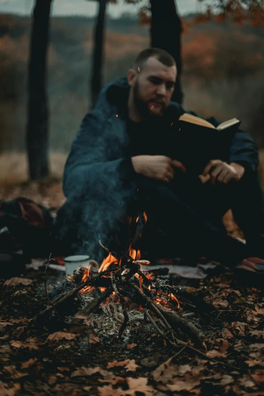 a man sitting in front of a campfire reading a book, pexels contest winner, a man wearing a black jacket, avatar image, lumberjack, religious