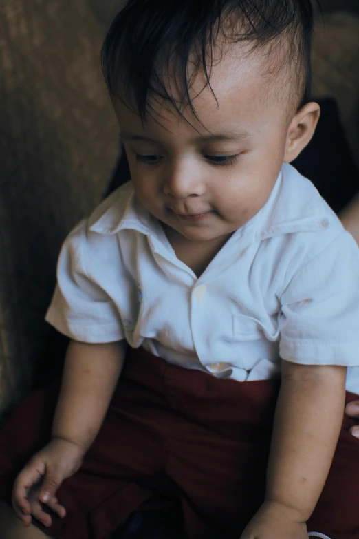 a baby sitting on top of a couch next to a woman, pexels contest winner, wearing school uniform, sri lanka, boy has short black hair, closeup - view