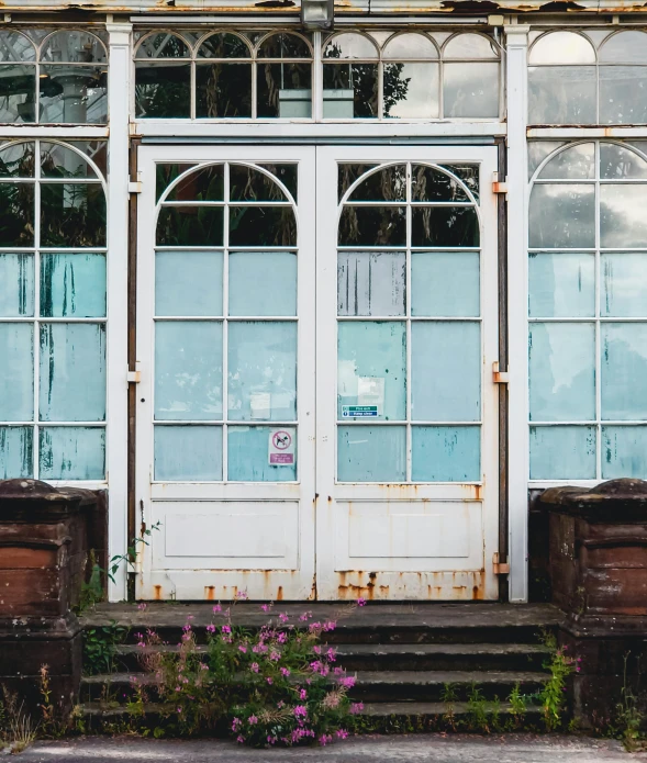 a red fire hydrant sitting in front of a building, an album cover, by Carey Morris, pexels contest winner, big french door window, greenhouse, white sweeping arches, rusty