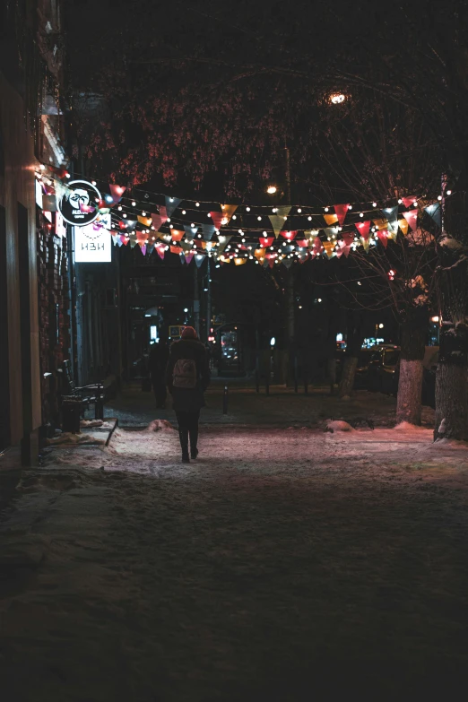 a person walking down a street at night, christmas lights, dimly lit cozy tavern, instagram picture, sovietwave aesthetic