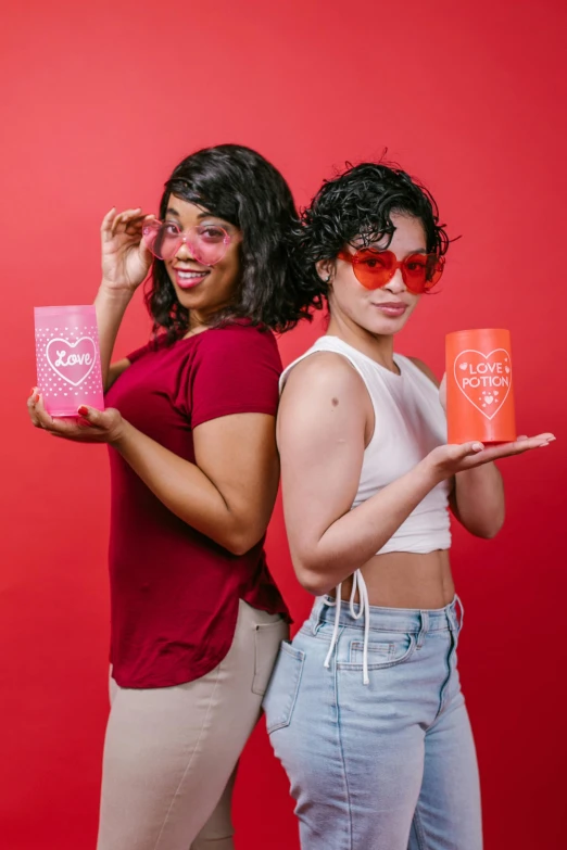 a couple of women standing next to each other, on a red background, pink glasses, campbell's soup can, latinas