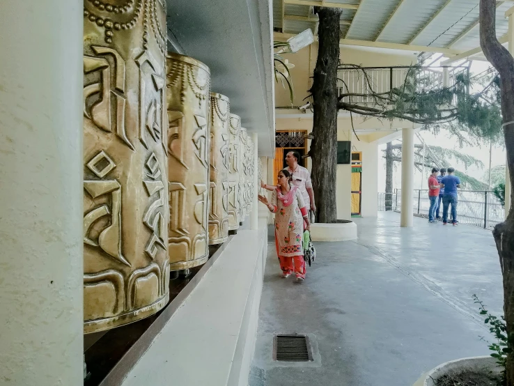 a couple of women standing next to each other, pexels contest winner, bengal school of art, pure gold pillars, background image, bells, health spa and meditation center