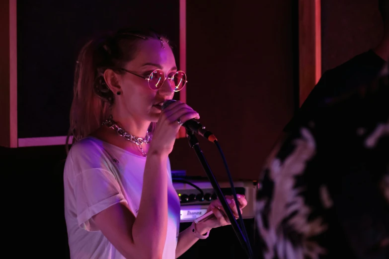 a woman singing into a microphone in front of a man, an album cover, by Alice Mason, pexels, antipodeans, sydney sweeney, panoramic, nightlife, she looks like a mix of grimes