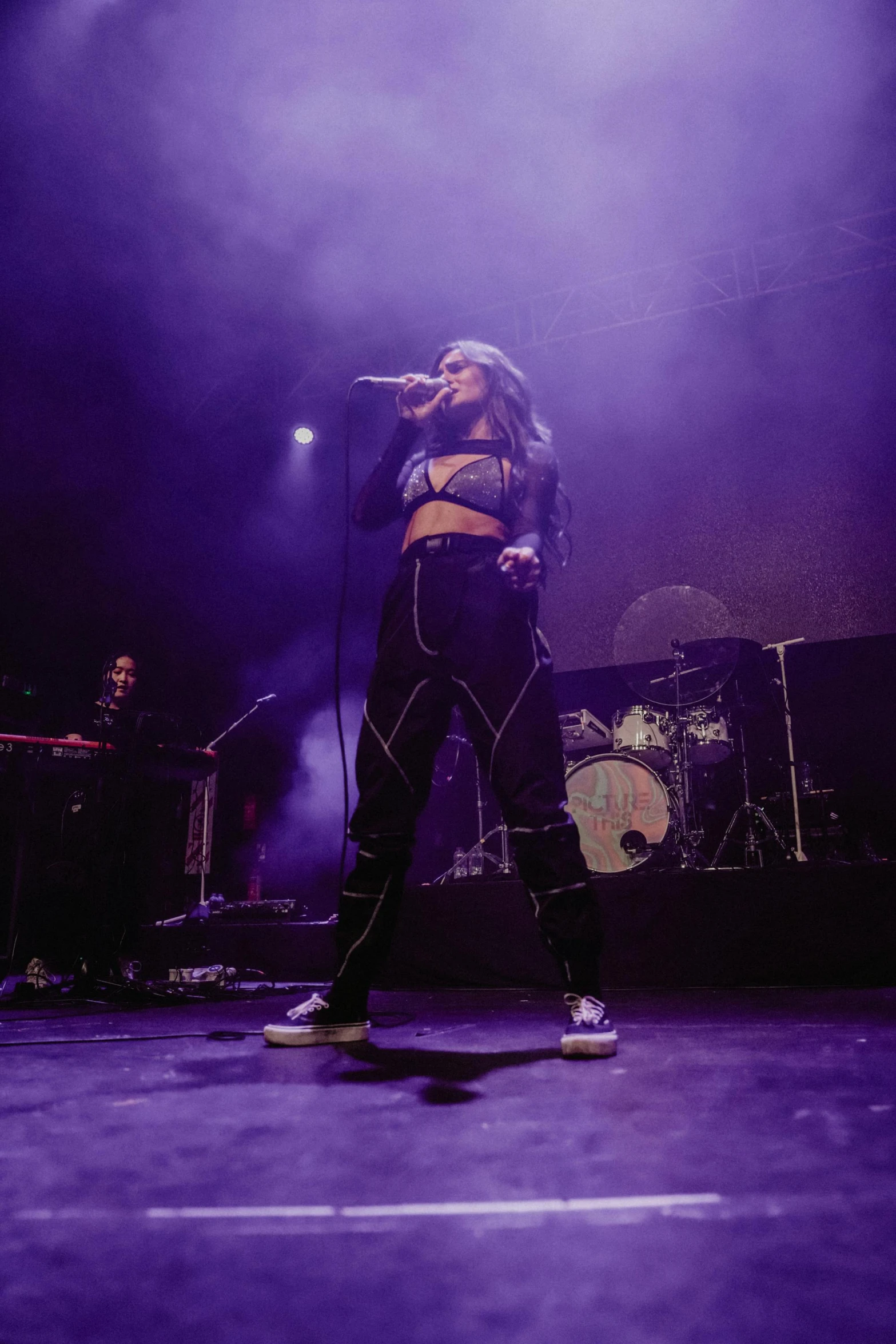 a woman standing on a stage with a microphone, an album cover, trending on pexels, soft devil queen madison beer, concert photography, galactic, violet myers