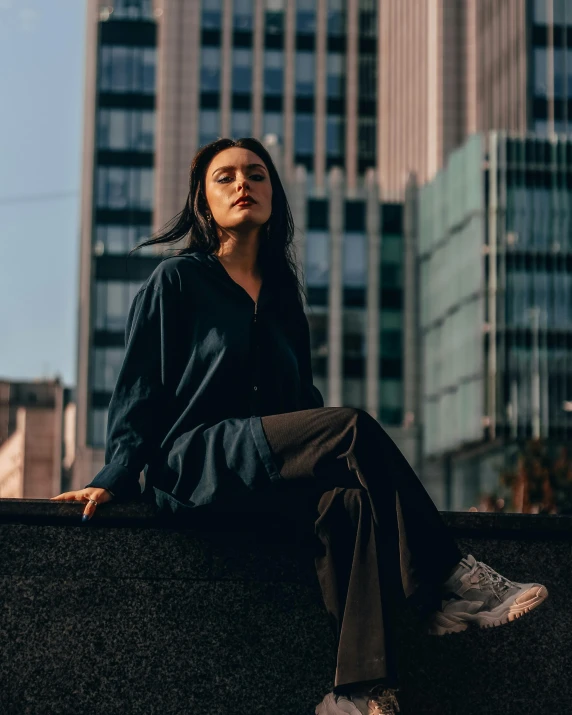 a woman sitting on a ledge in a city, an album cover, trending on unsplash, portrait androgynous girl, portrait sophie mudd, high quality photo, wearing human air force jumpsuit