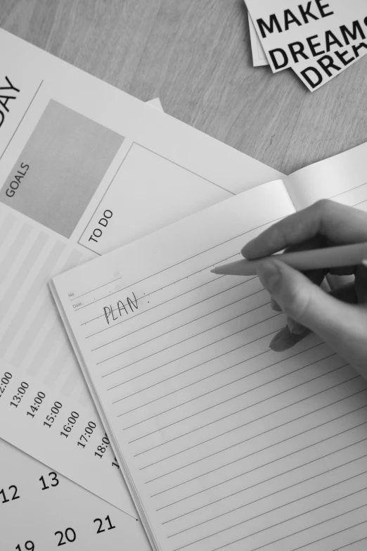 a black and white photo of a person writing in a notebook, planning, promo image, stacked image, flat lay