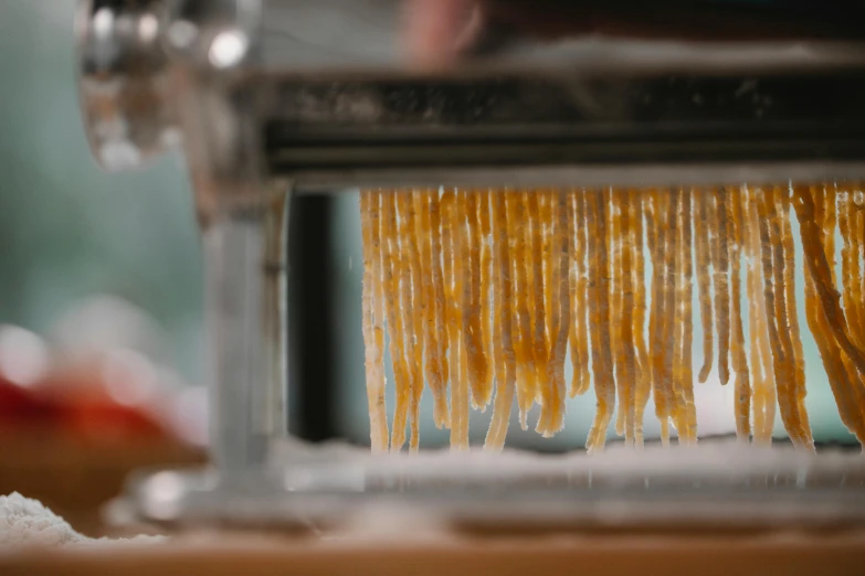 a close up of pasta being made by a machine, a portrait, by Daniel Lieske, unsplash, dripping stalagtites, marmalade, long flowing fabric, morning hour