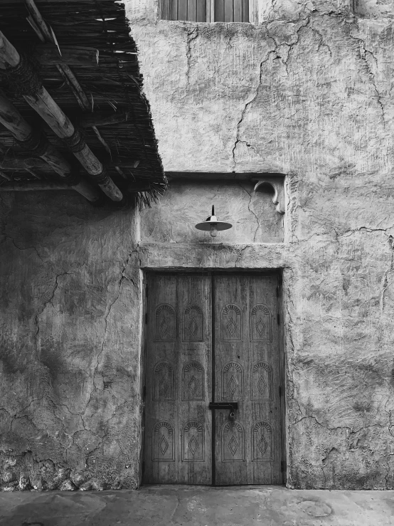 a black and white photo of an old building, by Jan Kupecký, pueblo architecture, wood door, by greg rutkowski, paul barson