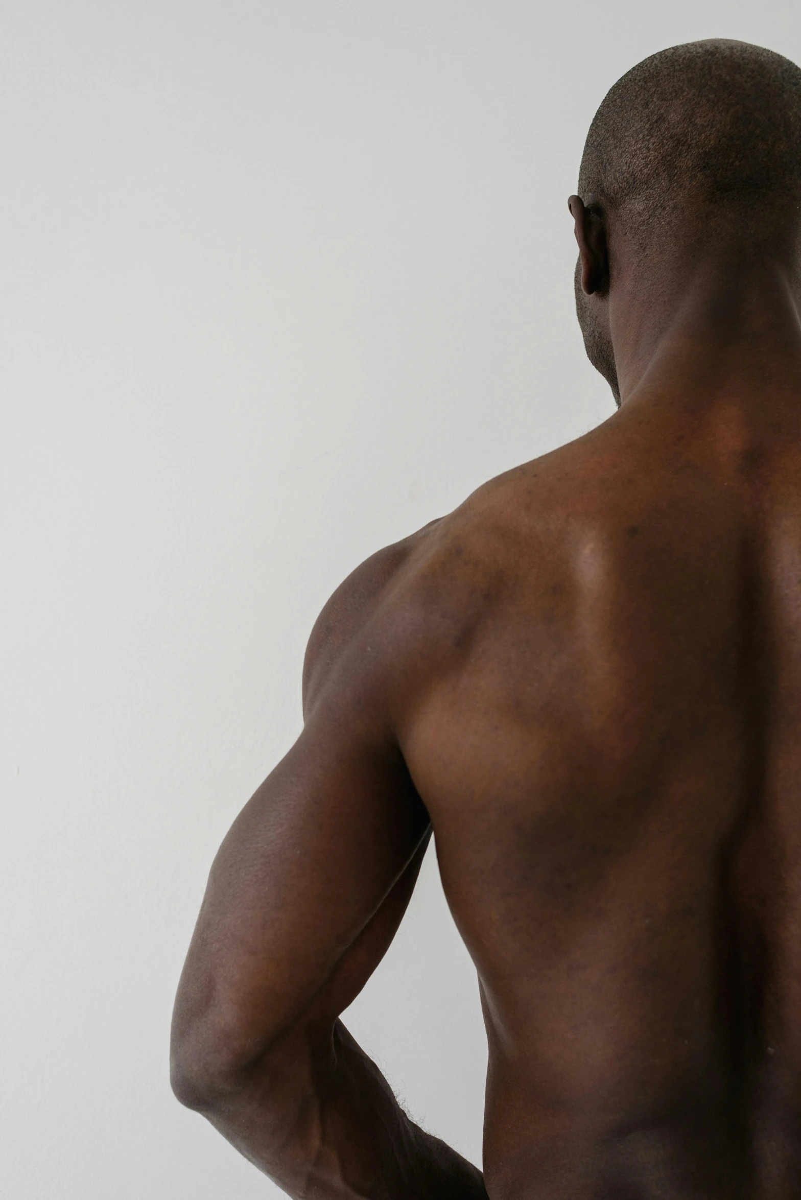 a man standing with his back to the camera, defined muscles, dark skin, background image, grey skinned