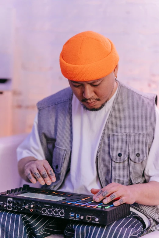 a man in an orange turban playing a musical instrument, an album cover, inspired by Zhu Da, unsplash, portrait of computer & circuits, turntablist, yanjun chengt, candid shot