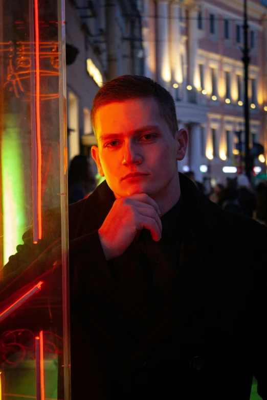 a man standing in front of a window with his hand on his chin, an album cover, by Sebastian Vrancx, on a street at night, vitalik buterin, lgbtq, red square