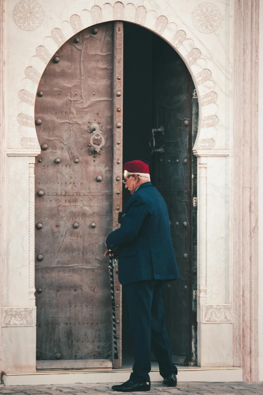 a man standing in front of a wooden door, mausoleum, top selection on unsplash, ornate turban, spying