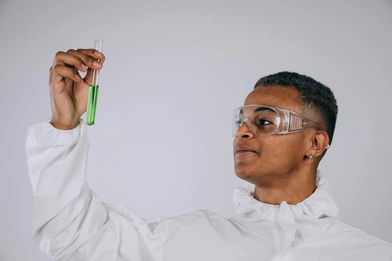 a man in a lab coat holding a test tube, trending on pexels, black teenage boy, androgynous person, full of greenish liquid, academic clothing