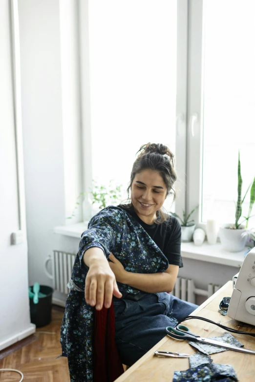 a woman sitting in front of a sewing machine, mutahar laughing, wearing casual clothes, profile image, aleksander rostov