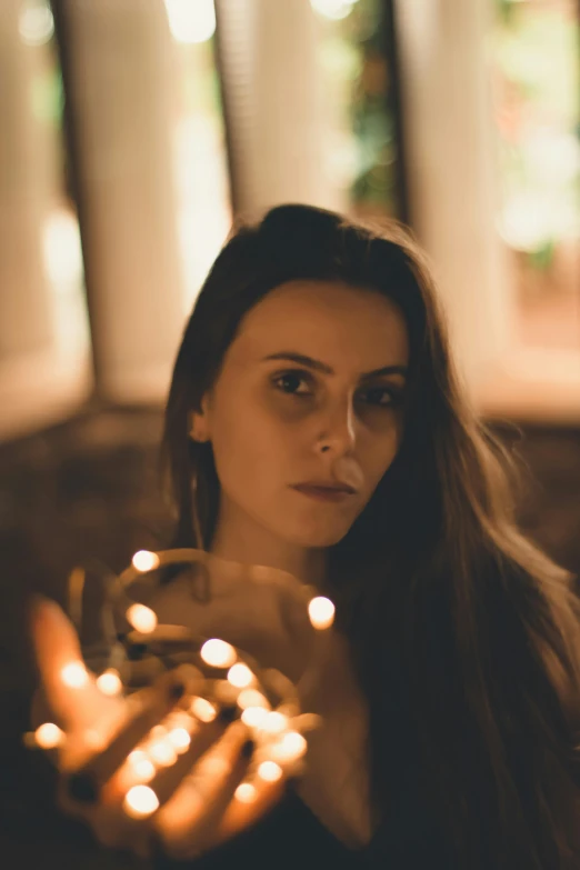 a woman holding a string of lights in her hands, a portrait, inspired by Elsa Bleda, pexels contest winner, renaissance, handsome girl, low quality photo, multiple stories, slightly pixelated