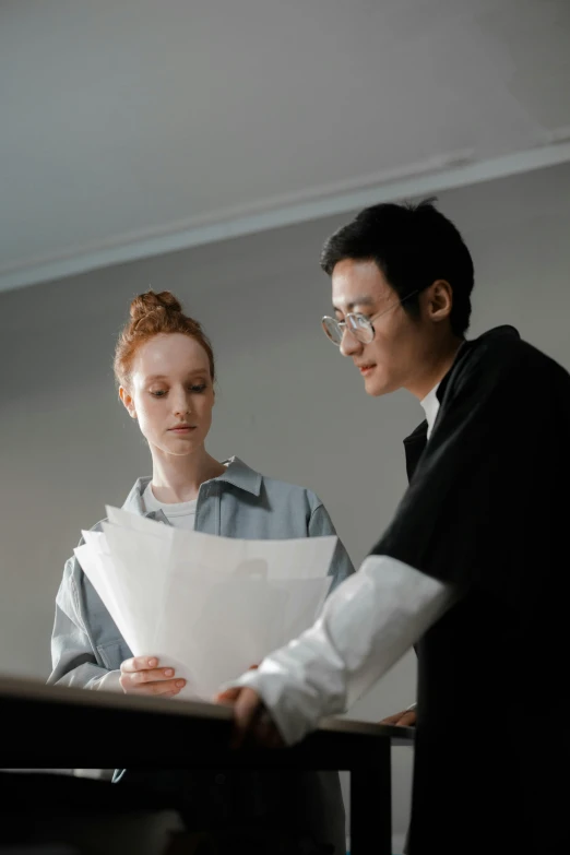 a man and a woman looking at a piece of paper, ryan jia, high-quality photo, studious, holding court