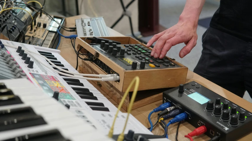 a man that is standing in front of a keyboard, inspired by John McLaughlin, synthetism, in a workshop, crusty electronics, in 2 0 1 8, a wooden