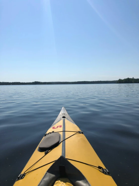 a yellow kayak sitting on top of a body of water, a picture, clear skies in the distance, vermilion and red lake, jenni pasanen, low quality photo