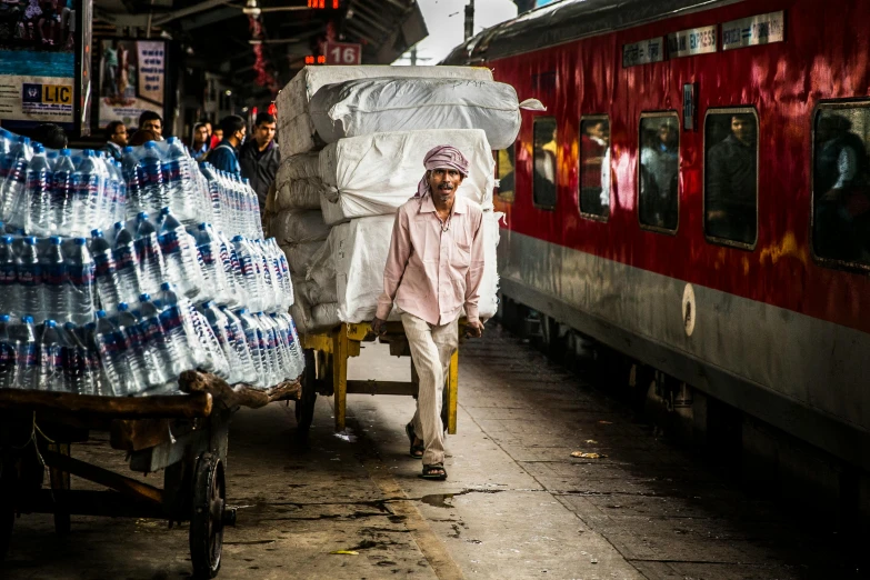 a man walking down a street next to a train, inspired by Steve McCurry, pexels contest winner, water to waste, on an indian street, thumbnail, busy market