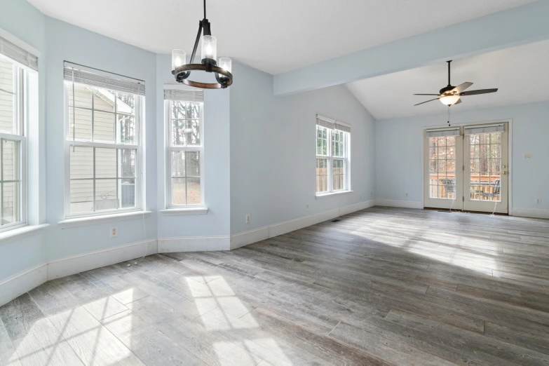 a living room with hardwood floors and a ceiling fan, by Carey Morris, unsplash contest winner, light and space, white grey blue color palette, empty floor, upscaled to high resolution, taken with canon 5d mk4