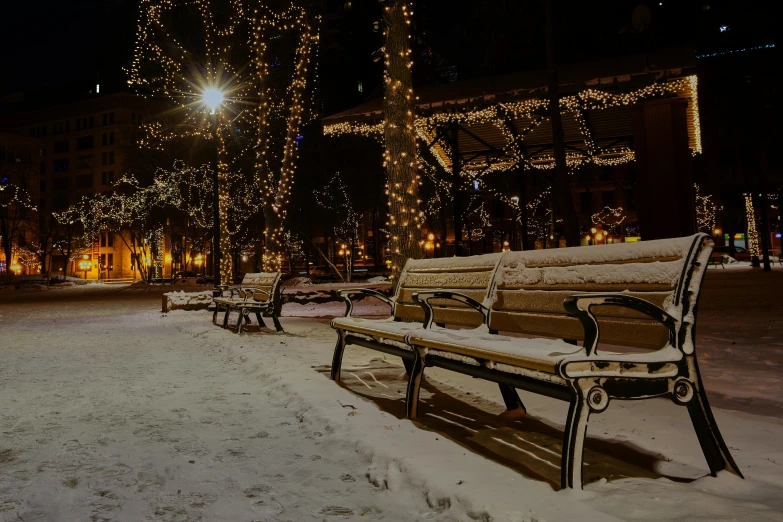 a couple of benches sitting on top of a snow covered ground, christmas lights, town square, unsplash photo contest winner, background image