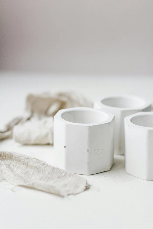 a couple of cups sitting on top of a table, inspired by Rachel Whiteread, unsplash, white concrete, hexagonal ring, 4 cannabis pots, detailed product photo