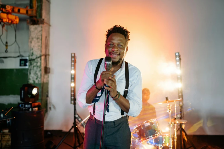 a man that is standing up with a microphone, an album cover, pexels, happening, godwin akpan, wedding, brightly-lit, posing for camera