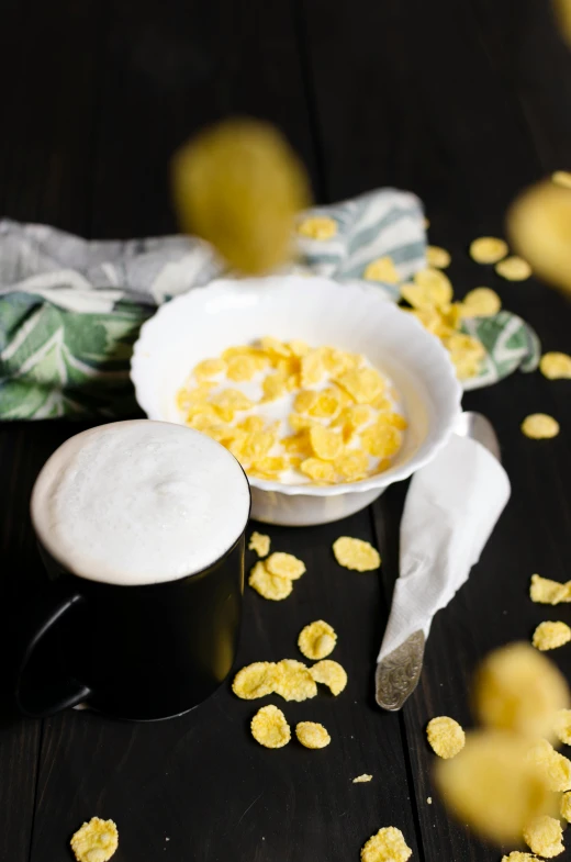 a bowl of cereal next to a cup of coffee, by Matthias Stom, unsplash, dau-al-set, black and yellow, petals, yogurt, clover