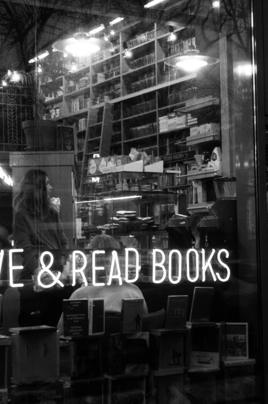 a store window with a neon sign reading love and read books, a black and white photo, unsplash, lowbrow, eve, book shelves, 1 8 6 0 s, an olive skinned