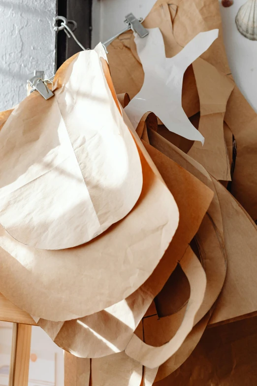 a bunch of paper bags sitting on top of a wooden table, by Jessie Algie, trending on unsplash, gutai group, leather apron, cone shaped, beige, organic shape