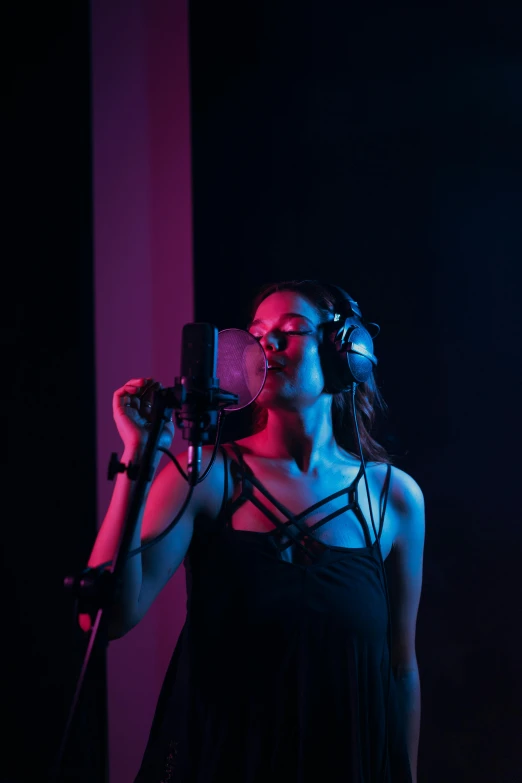 a woman in a black dress singing into a microphone, an album cover, by Robbie Trevino, pexels, studio lighting 4 k, with headphones, loish |, behind the scenes