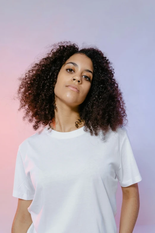 a woman standing with her hands in her pockets, an album cover, pexels contest winner, white t-shirt, aida muluneh, headshot profile picture, curls