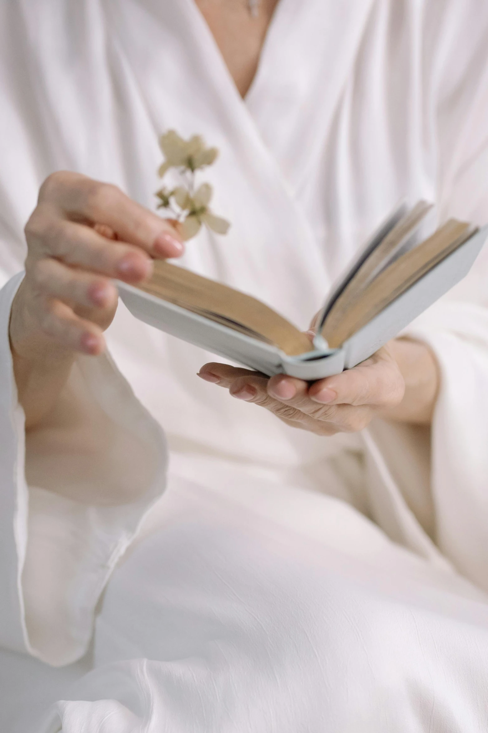 a woman in a bathrobe reading a book, inspired by Hedda Sterne, holding magic flowers, white hanfu, zoomed in shots, medium-shot