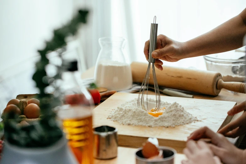 a group of people preparing food on a table, a still life, by Liza Donnelly, trending on pexels, whipped cream on top, spatula, manuka, on a wooden desk