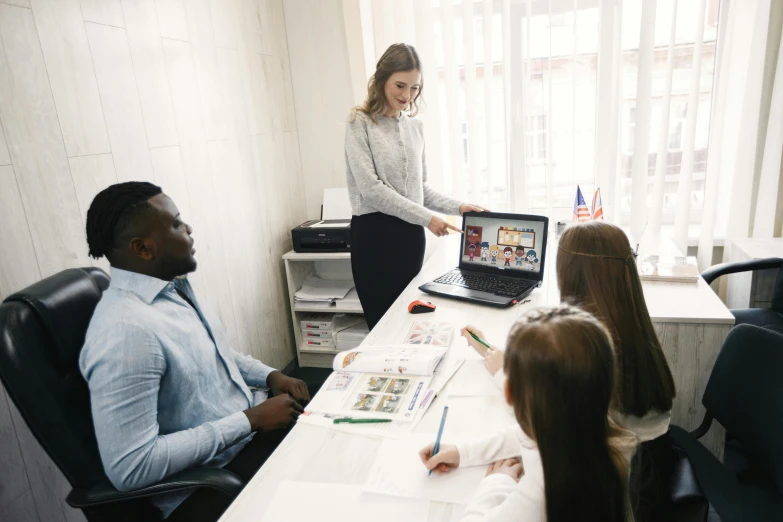 a group of people sitting around a table with a laptop, on a white table, school curriculum expert, profile image, thumbnail