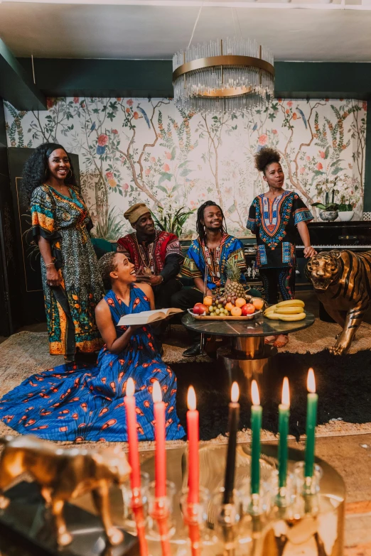 a group of people sitting around a table with candles, by Ella Guru, pexels contest winner, black arts movement, wearing an african dress, wearing festive clothing, standing still, promotional shot