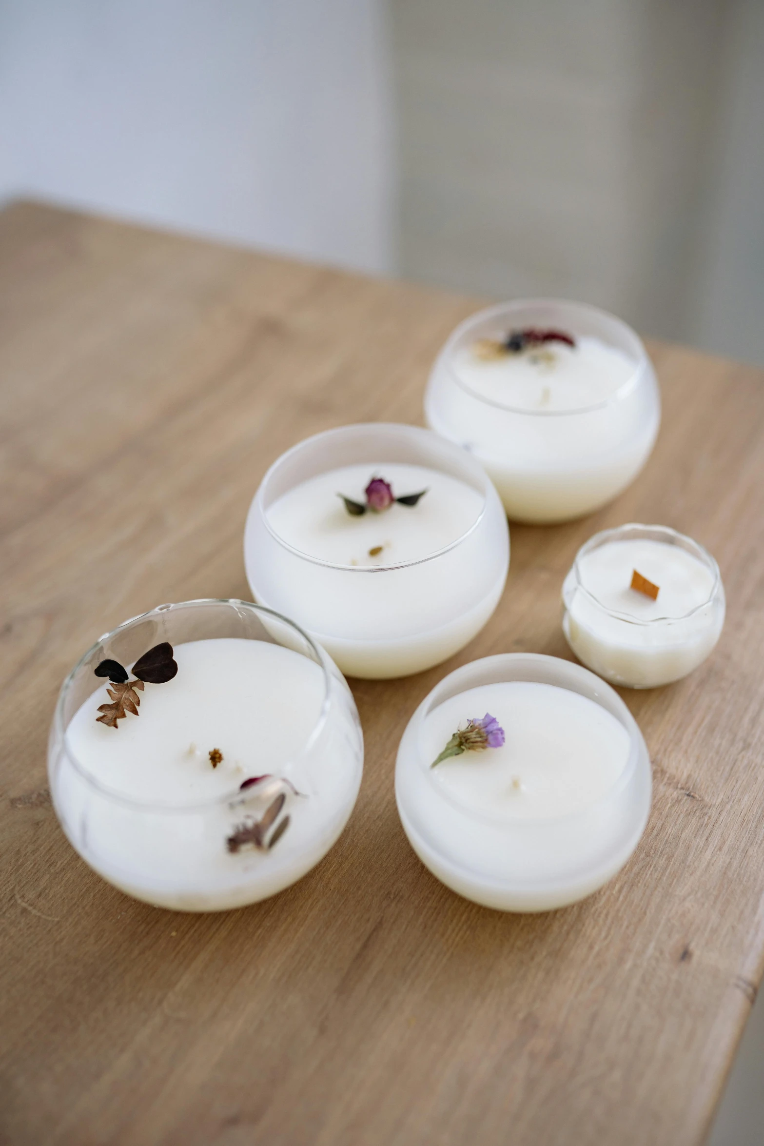 a group of candles sitting on top of a wooden table, detailed product image, sleek white, floating pieces, recipe