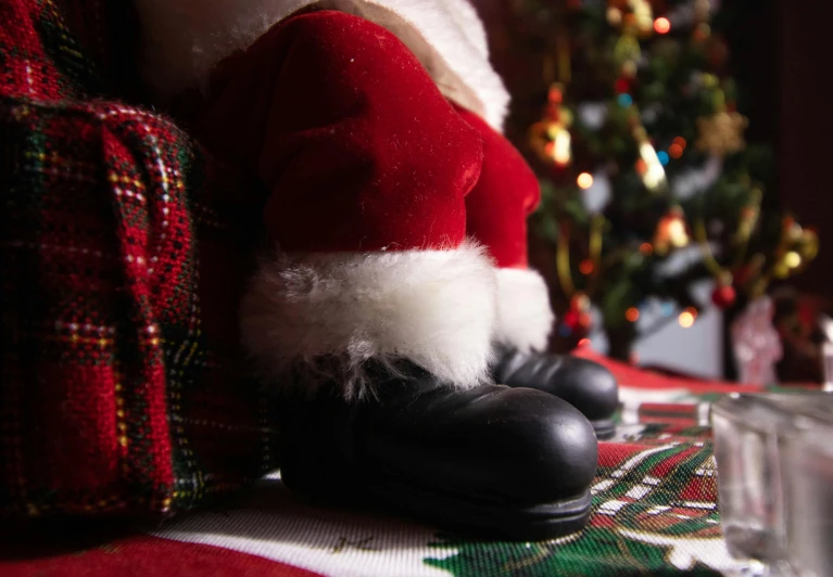 a santa clause sitting on a couch next to a christmas tree, by Alice Mason, pexels contest winner, black leather boots, extreme closeup shot, standing on a shelf, toys