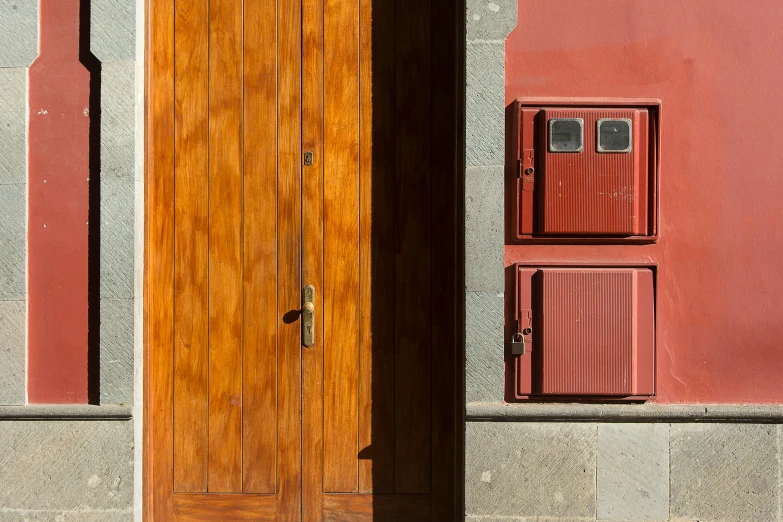 a wooden door sitting on the side of a building, by Sven Erixson, pexels contest winner, postminimalism, payne's grey and venetian red, madrid, two wooden wardrobes, red and yellow light