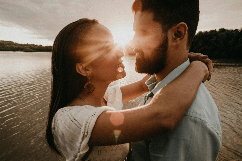 a man and woman standing next to each other in front of a lake, pexels contest winner, happening, golden hour closeup photo, smiling at each other, radiant halo, wildly attractive