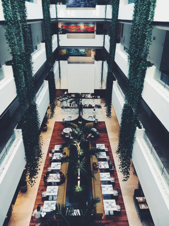 a dining room filled with lots of tables and chairs, inspired by Tomàs Barceló, unsplash, atrium, thumbnail, jakarta, high view