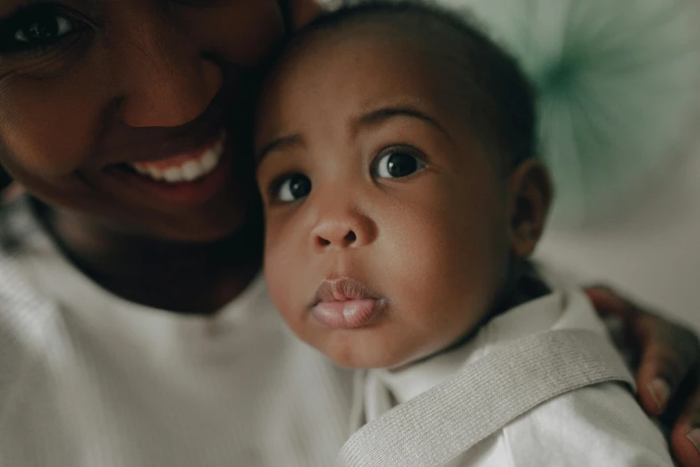 a woman holding a baby in her arms, pexels contest winner, african facial features, middle close up, rectangle, smaller mouth