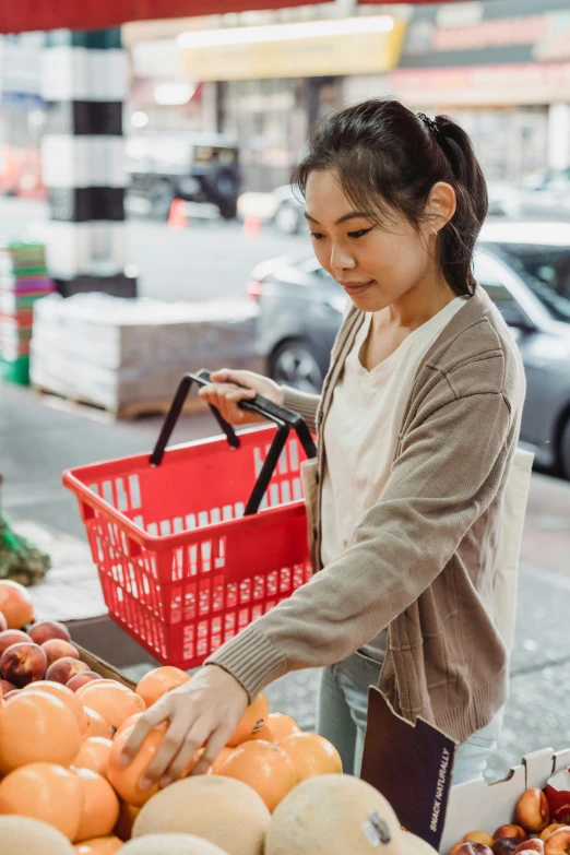 a woman is shopping in a grocery store, pexels contest winner, wearing an orange t-shirt, asian female, fruit basket, australian